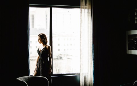 a woman standing near a window looking outside