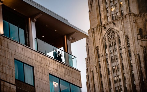 a man and woman standing on a balcony looking at the city