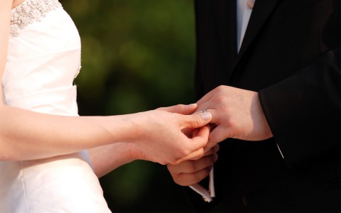 close up of a man and woman holding hands at a wedding