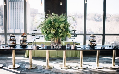 a long black and gold table with a big green floral centerpiece in the middle