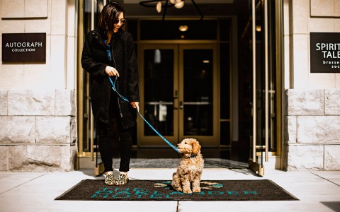 a woman standing with her dog in front of the entrance to a building