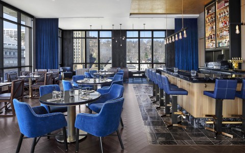 a lounge area with tables and blue velvet chairs