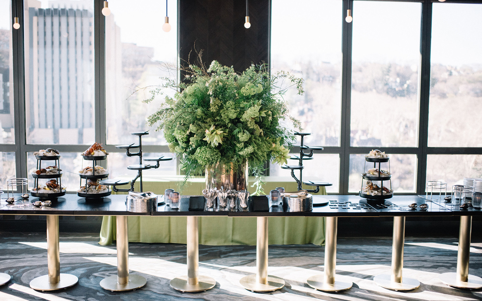 gallery a long black and gold table filled with a variety of food and a large green centerpiece in the middle
