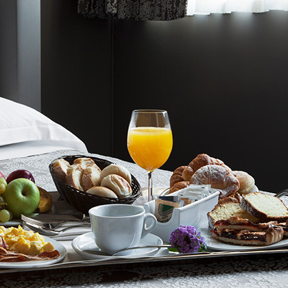 a close up of a tray on a bed filled with a variety of breakfast foods and drinks