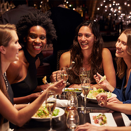 a group of women dining and smiling while sitting outside at night