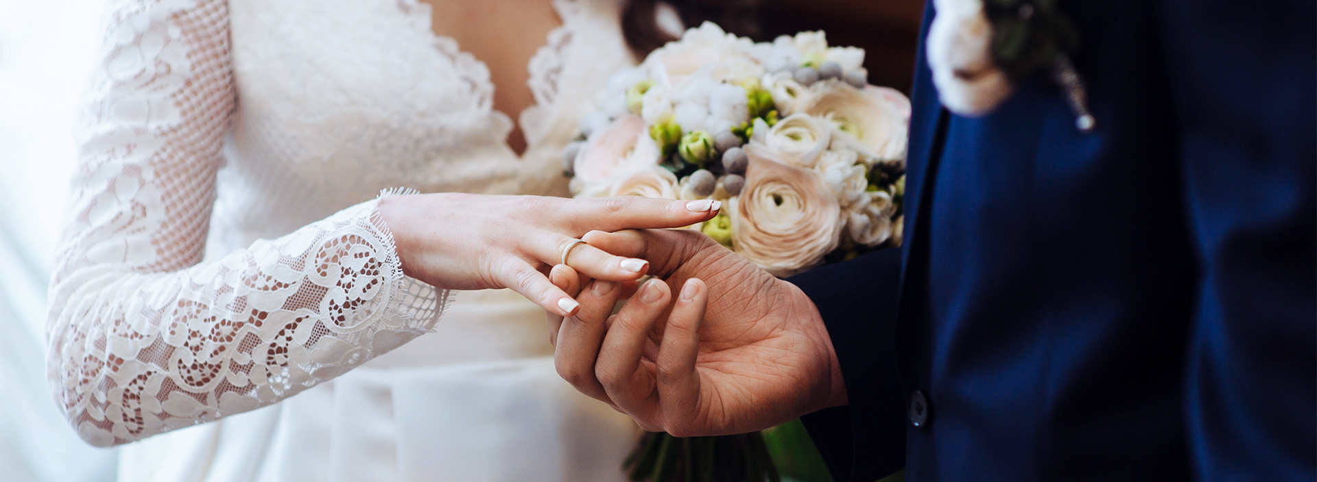 close up of a groom putting a ring on the bride