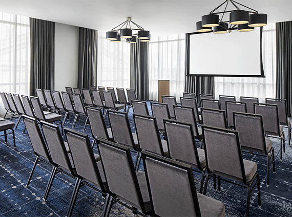 a room with rows of chairs and a projection screen in front