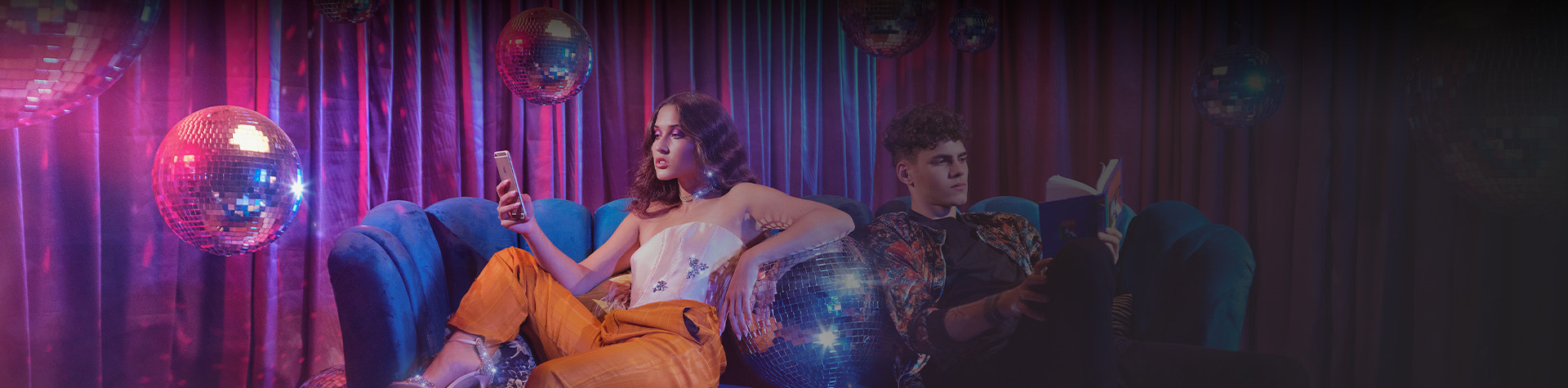 man and woman sitting on blue chairs with disco balls around them 