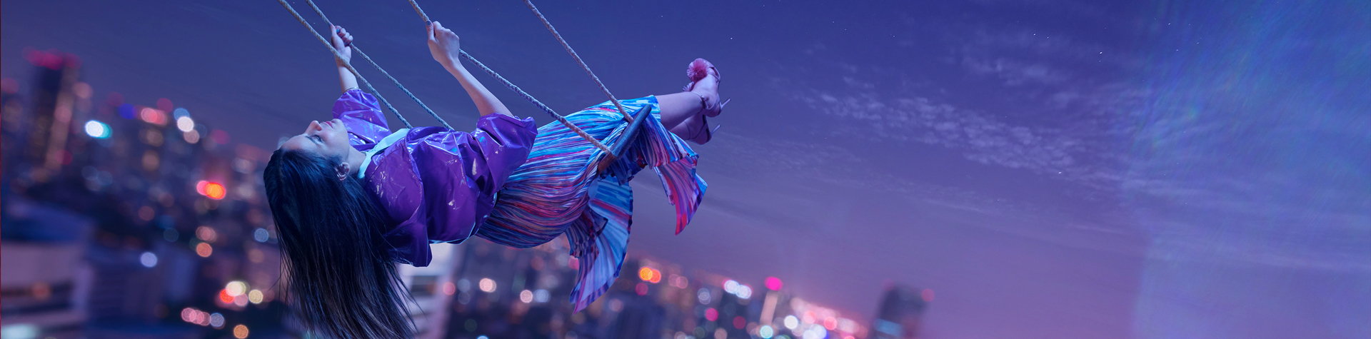 woman on a swing with a night view at background