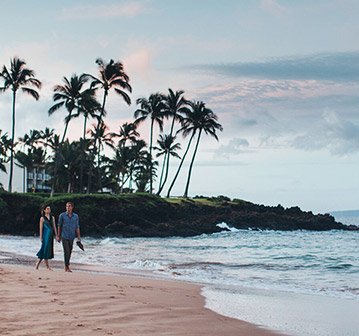 couple walking by the shore during sunset